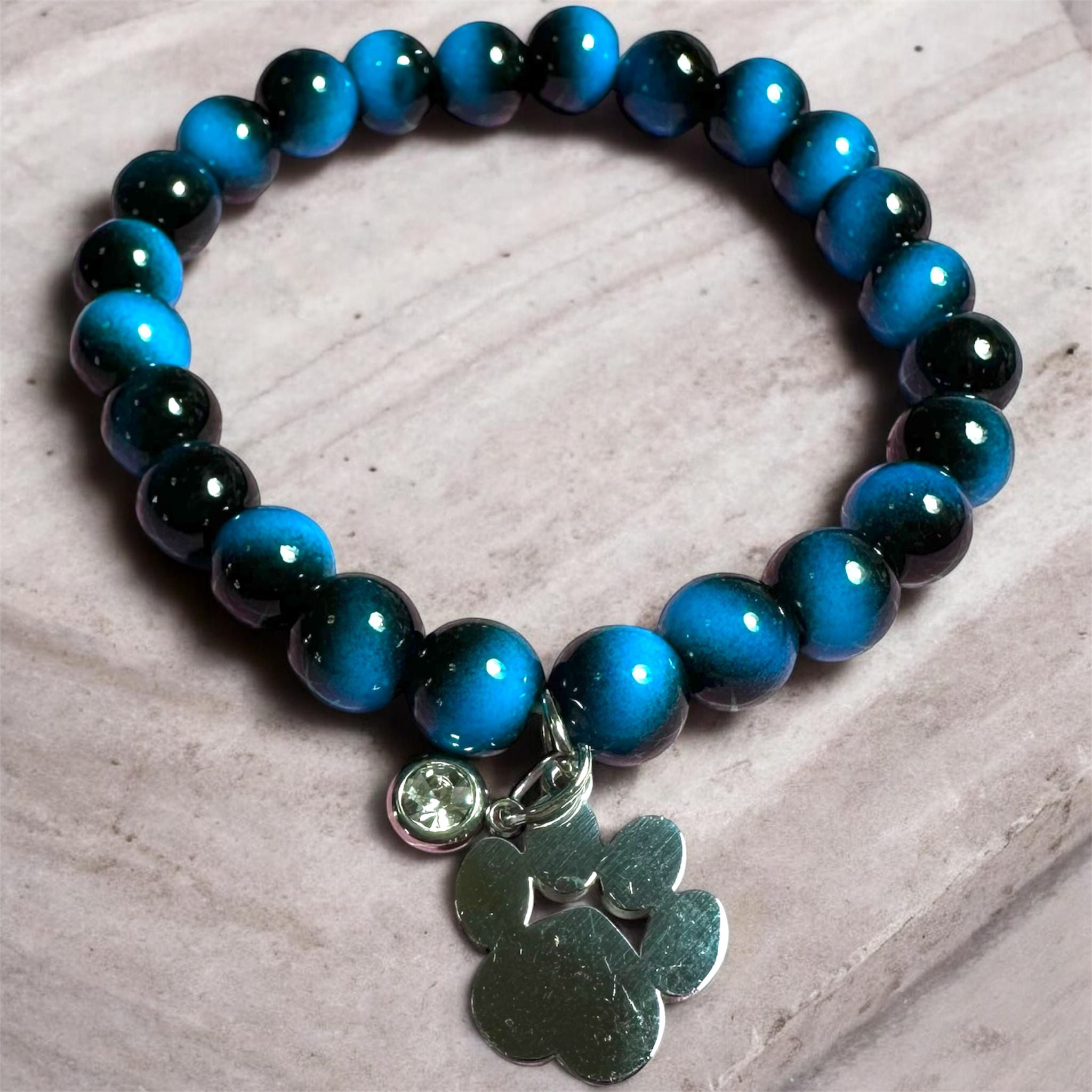 Pulsera elástica con cuentas en azul y negro con dije de huellita en Acero Inoxidable hecha a mano